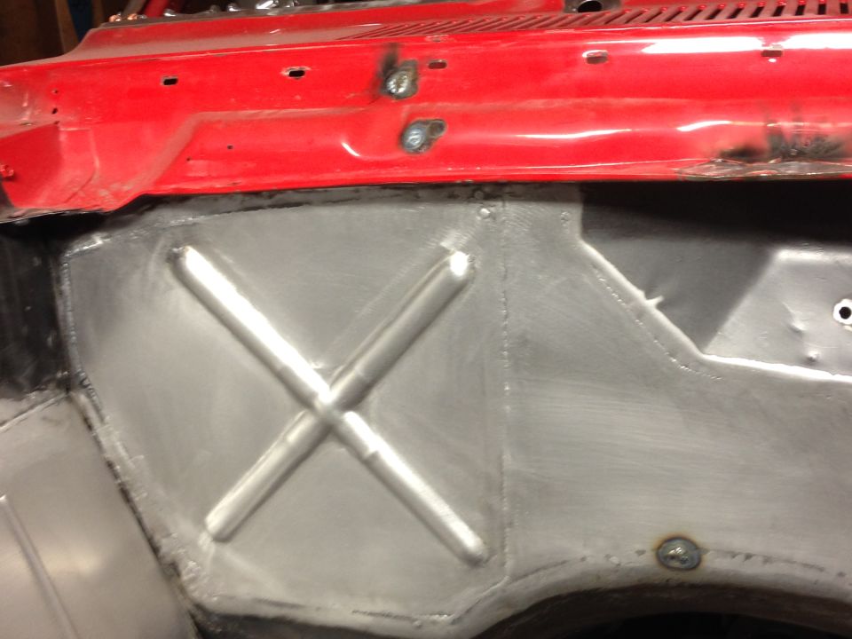 Red car body panel with welded metal reinforcement