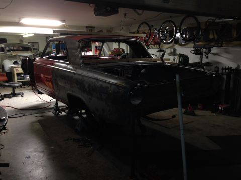 1964 Ford Fairlane - Car body on jack stands in garage, possibly undergoing restoration. Another vehicle is in the background.