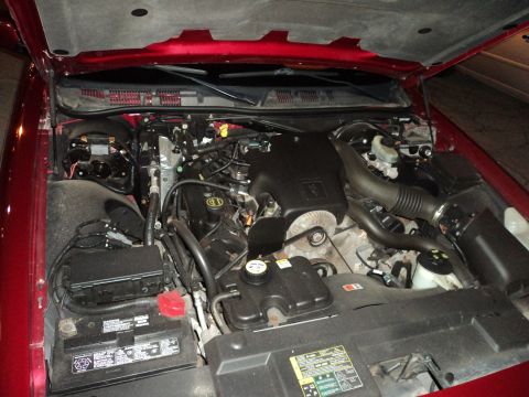 2004 Mercury Grand Marquis - The engine bay of a red 2004 Mercury Grand Marquis is visible with the hood raised.