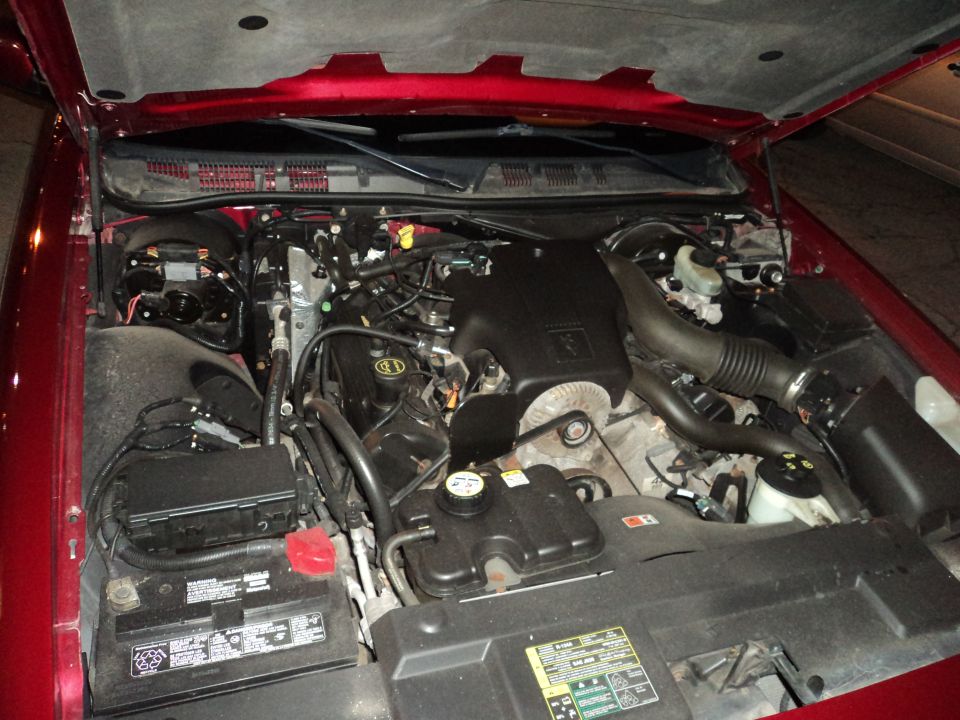 Red 2004 Mercury Grand Marquis engine bay with hood open, showing engine components and battery