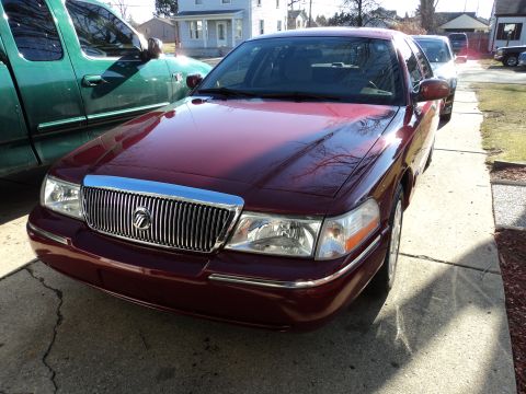 2004 Mercury Grand Marquis - A maroon 2004 Mercury Grand Marquis is parked next to a green pickup truck.