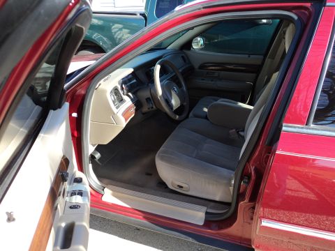 2004 Mercury Grand Marquis - The interior of a red Mercury Grand Marquis is shown with the driver's door open, revealing the seats and dashboard.
