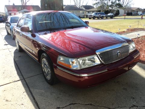 2004 Mercury Grand Marquis - A red Mercury Grand Marquis is parked on a driveway with another car behind it.