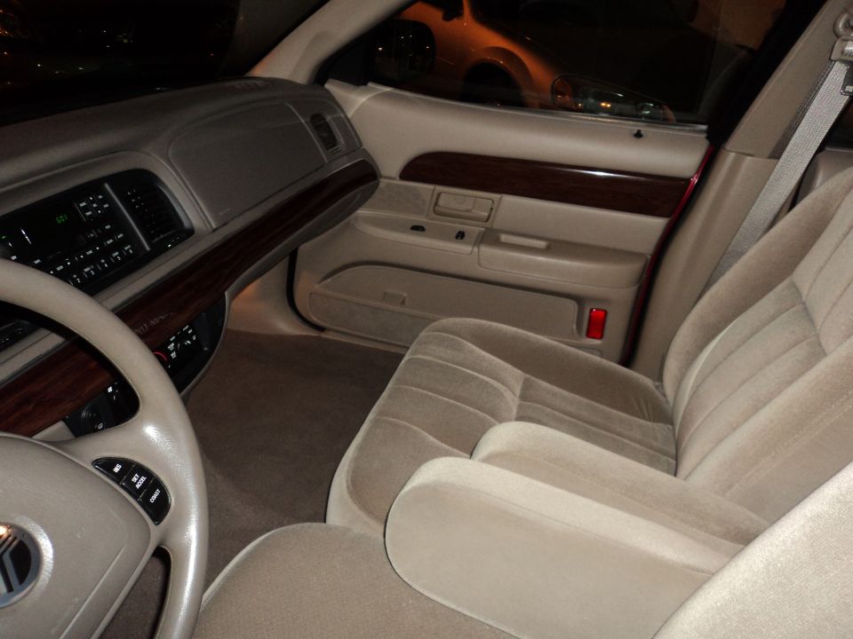Interior shot of a 2004 Mercury Grand Marquis, showing the driver's side dashboard, steering wheel, and front passenger seat
