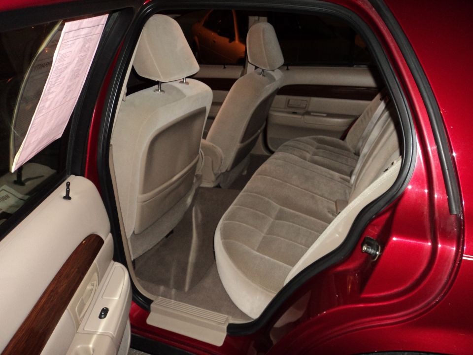 Red sedan interior with tan cloth seats, wood trim on door panels, and a pink paper on the driver's side window