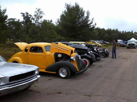 1935 Chevrolet new - A line of vintage automobiles are parked outdoors under a cloudy sky.