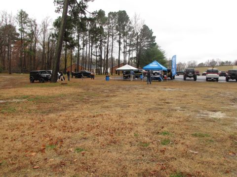 1979 Ford Bronco - An outdoor event features several vehicles and tents under a cloudy sky.