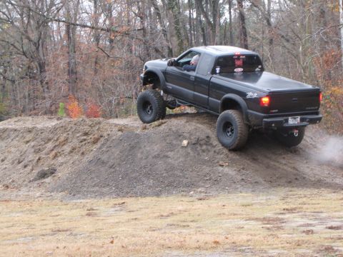 1979 Ford Bronco - A modified black pickup truck navigates an off-road course with large tires and lifted suspension.