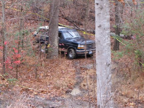 1979 Ford Bronco - Ford F-150 truck is stuck off-road in a wooded area with caution tape around.