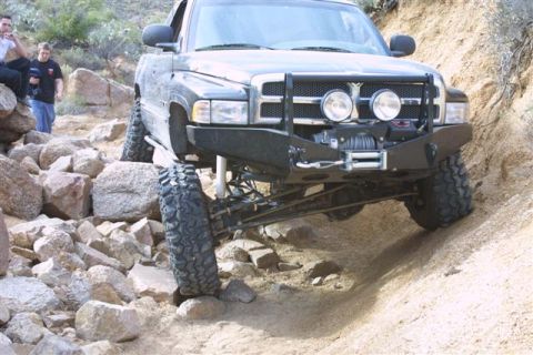 1994 Ford Bronco - Pickup truck with large tires and off-road modifications on a dirt trail.
