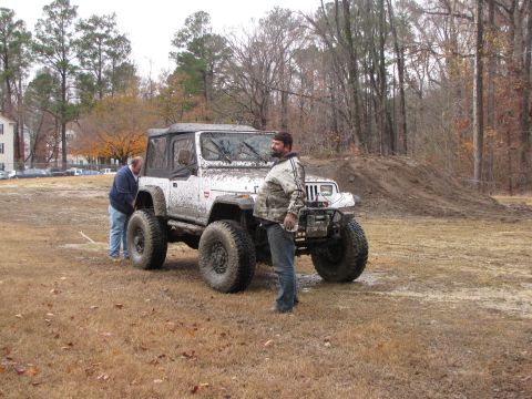 1979 Ford Bronco - A white Jeep Wrangler modified for off-road use sits in a muddy field.