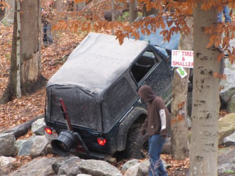 1979 Ford Bronco - Off-road vehicle attempts to navigate a difficult rocky course, with a sign indicating tire size restrictions.