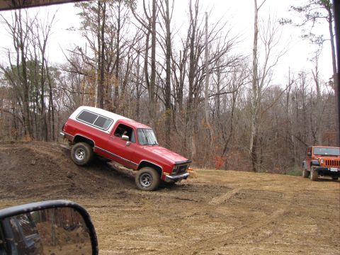 1979 Ford Bronco - A red SUV navigates an off-road trail with another vehicle visible in the distance.