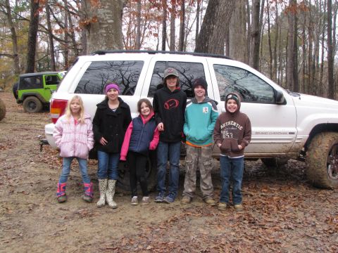 1979 Ford Bronco - A group of children pose in front of a white Jeep Grand Cherokee, with a green Jeep visible in the background.