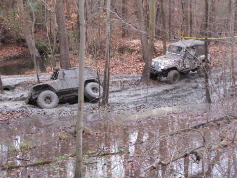 1979 Ford Bronco - Two off-road vehicles are stuck in the mud on a wooded trail after a day of off-roading.