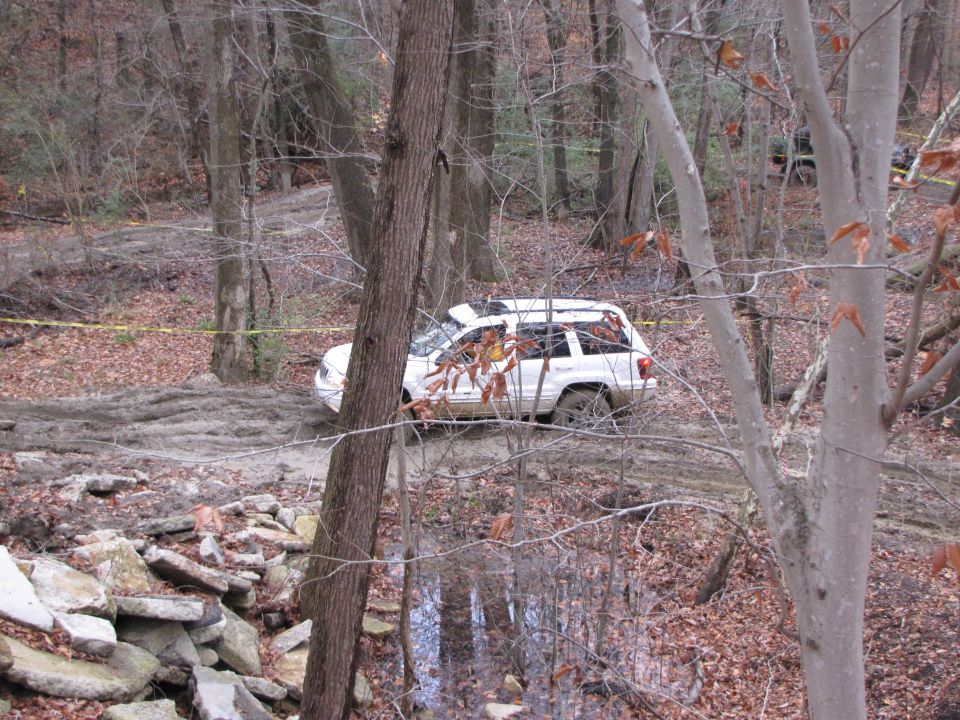 White SUV navigating a muddy forest trail