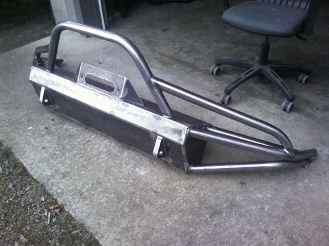 1989 Ford Bronco - A custom steel bumper with a brush guard and winch cutout sits on a concrete surface.