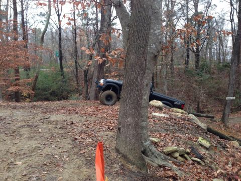 1979 Ford Bronco - A black pickup truck navigates a challenging off-road course in a wooded area.