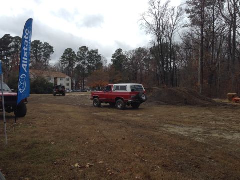 1979 Ford Bronco - Red and white SUV with spare tire on back, parked outdoors on a dirt lot. Another vehicle is in the background.
