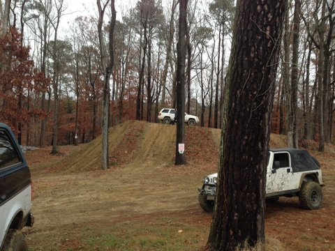 1979 Ford Bronco - Multiple SUVs navigate an off-road course in a wooded area.