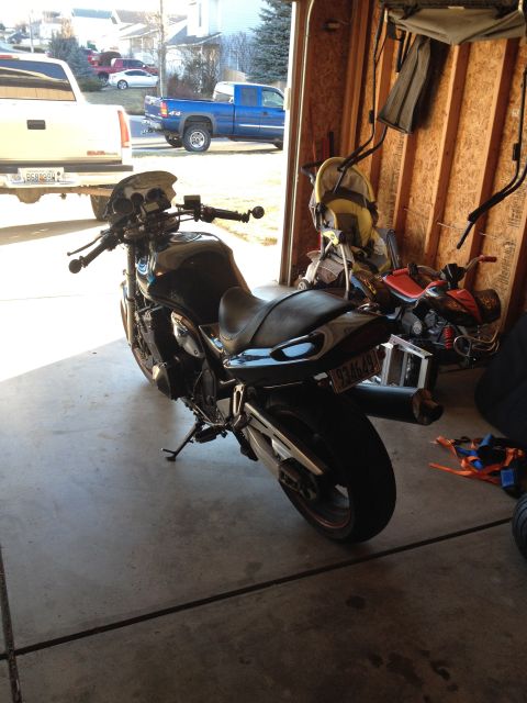 1998 Suzuki Bandit - A black motorcycle is parked in a garage, with other vehicles and items visible in the background.