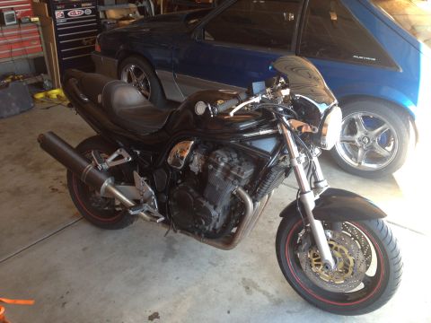 1998 Suzuki Bandit - A black 1998 Suzuki Bandit motorcycle is parked in a garage next to a blue Ford Mustang.