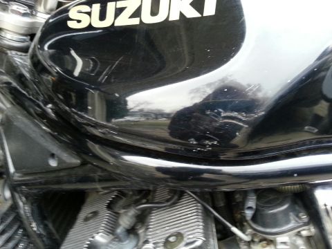 1998 Suzuki Bandit - Close-up of a 1998 Suzuki Bandit motorcycle fuel tank showing the SUZUKI logo and some wear.