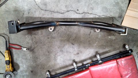 1967 Ford F-250 - A metal frame part lies on a concrete surface with an angle grinder and pliers nearby.