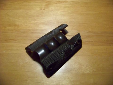 1995 Mercury Grand Marquis - A black gun grip with textured sides and finger grooves is shown on a wooden surface.