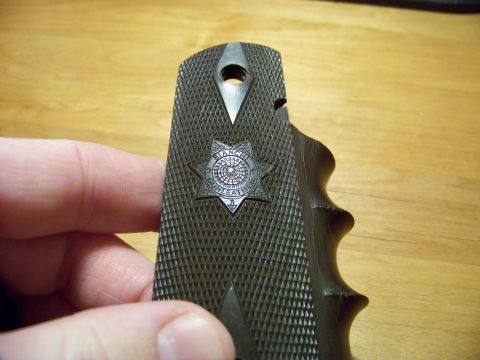 1995 Mercury Grand Marquis - A hand holds a dark gun grip with a textured surface and a central star emblem.
