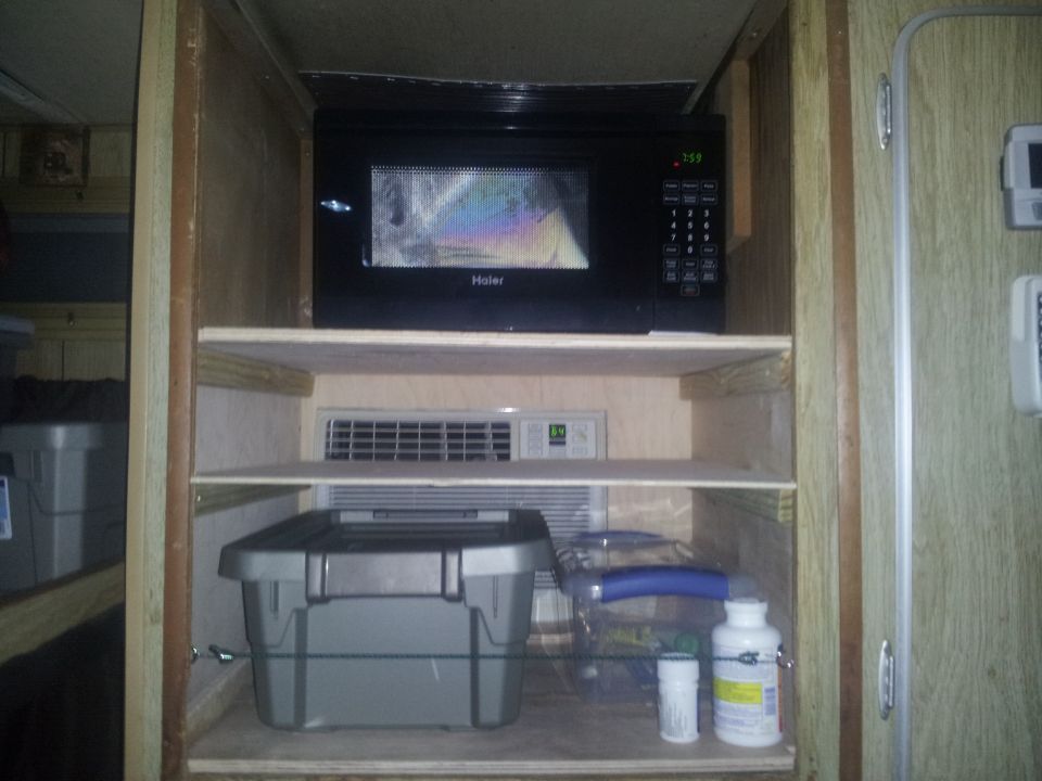 Interior shelves with Haier microwave, storage bins, and bottles