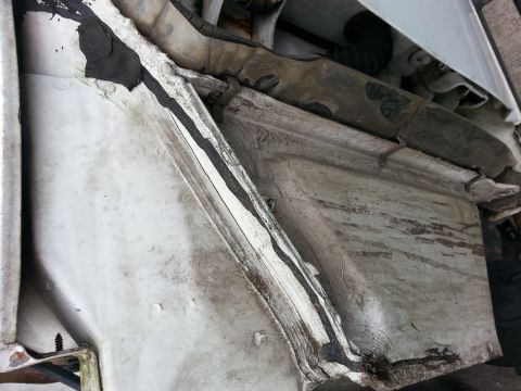 1992 Ford Bronco - The undercarriage of a white vehicle displays significant rust and sealant degradation.