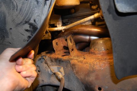 1985 Mercury Grand Marquis - Close-up view of the exhaust system and mounting bracket, showing signs of rust and wear.