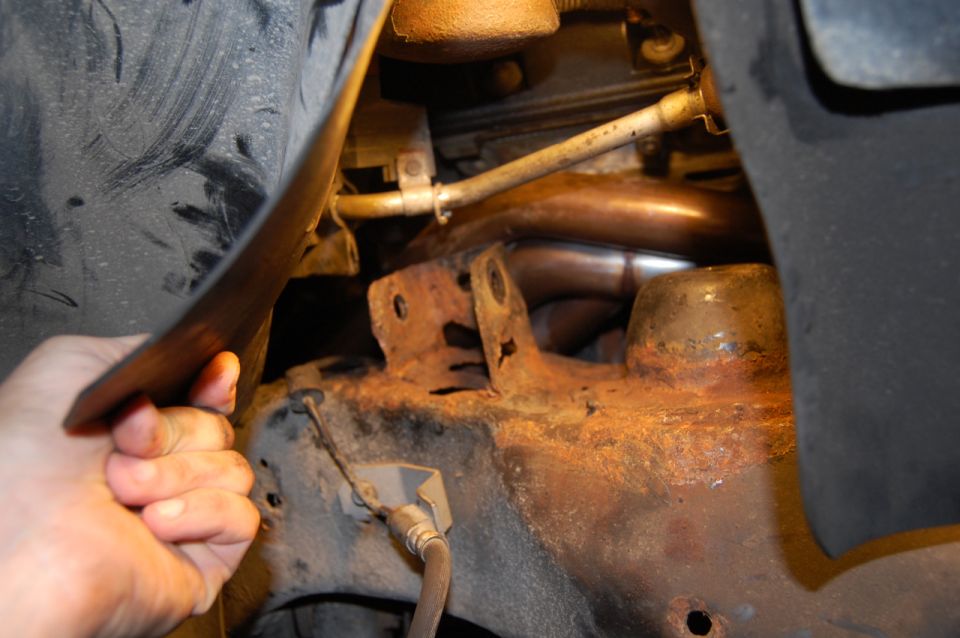 Exhaust pipe and rusty bracket under a vehicle