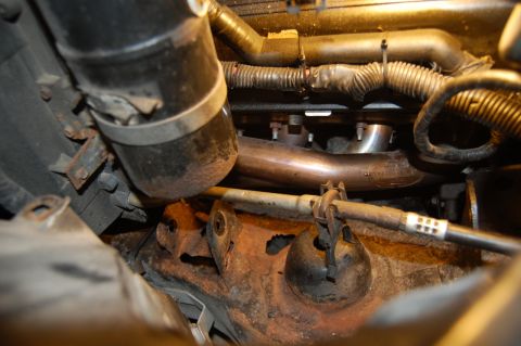 1985 Mercury Grand Marquis - Engine compartment detail showing exhaust manifold, pipes, and associated wiring and hoses.