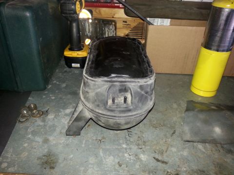 1992 Ford Bronco - A close-up of a plastic vacuum reservoir part, likely from a vehicle, is shown on a workshop floor.
