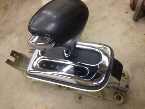 1998 Ford Crown Victoria - automatic shifter assembly with a black leather knob and chrome PRND21 gate bezel sitting on a concrete floor.