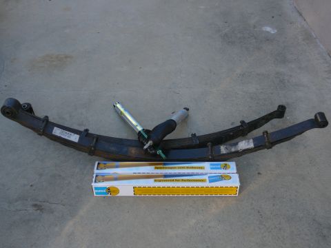 1988 Ford Bronco - New suspension parts, including leaf springs and shock absorbers, are displayed on the ground.