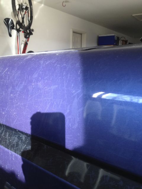 1996 Ford Bronco - A close-up of the scratched, purple paint on a vehicle, possibly a 1996 Ford Bronco, is shown. A black trim piece runs horizontally across…