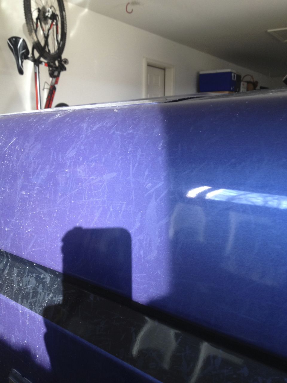 Scratched purple paint on a vehicle with black trim and a shadow.