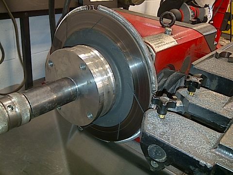 1995 Ford Probe - A close-up view of a brake rotor being machined on a lathe. The rotor is mounted on a hub assembly, and a cutting tool is positioned to res…
