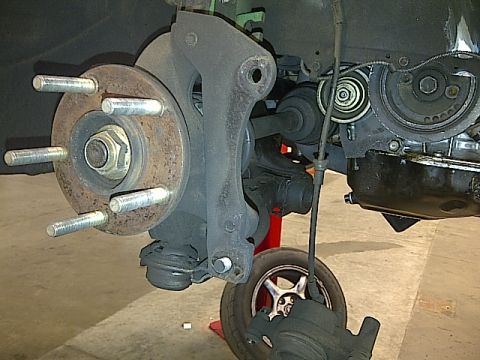 1995 Ford Probe - A close-up view of a vehicle's front wheel hub assembly, showing the brake rotor, wheel studs, and part of the suspension system. The engin…