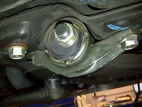 1995 Ford Probe - This is a close-up, low-angle shot of the underside of a vehicle's suspension system, focusing on a large bolt and bushing assembly. The su…