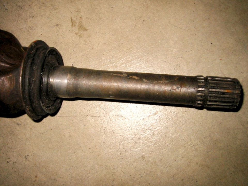 Splined metal driveshaft with rubber boot flange on concrete floor