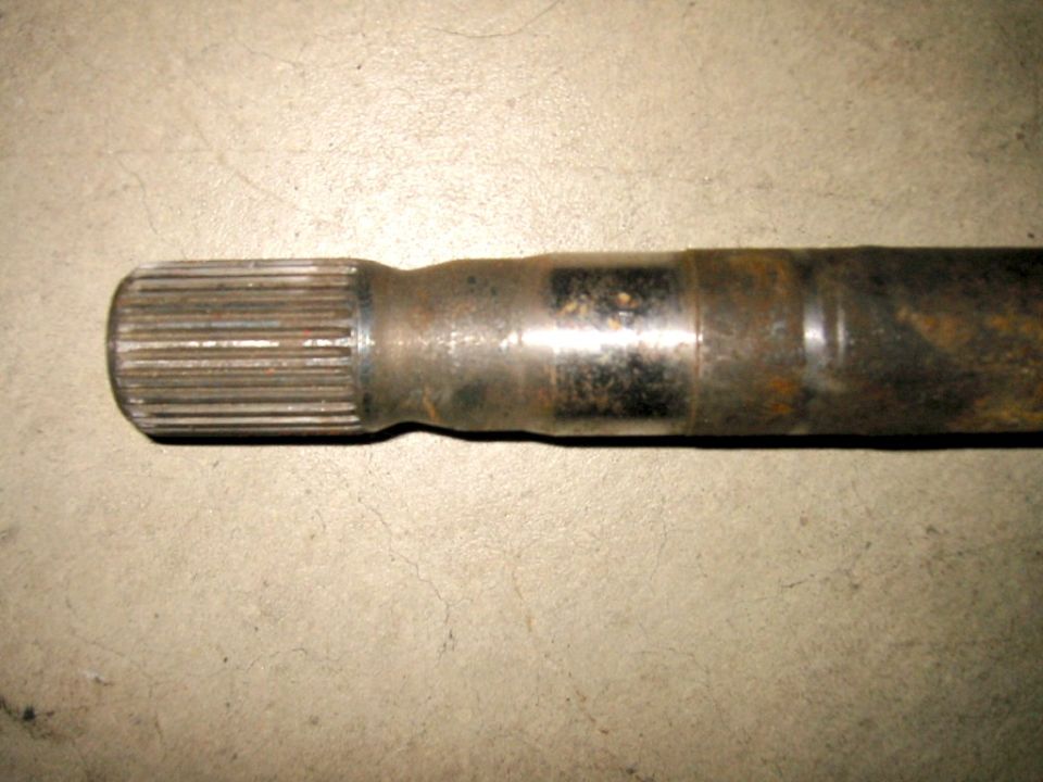 Splined axle shaft end with rust and grease on concrete floor