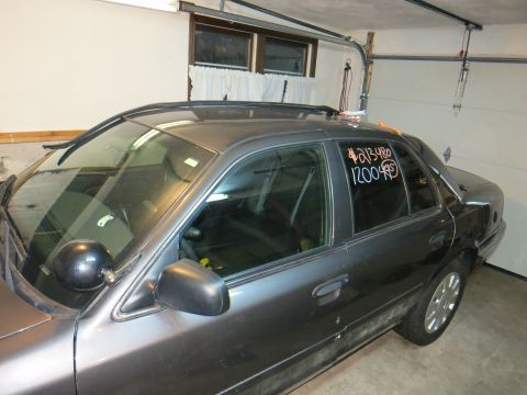 1991 Ford LTD Crown Victoria - Photograph of a gray sedan in a garage with a sale price on the window, not a document.