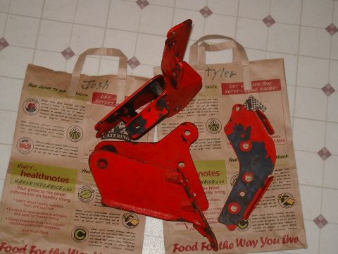 1991 Ford Bronco - Several red metal brackets are displayed on paper bags, showing signs of wear and chipped paint.