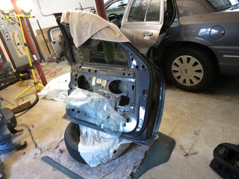 1991 Ford LTD Crown Victoria - Photograph of a detached car door propped in a garage, not a document.