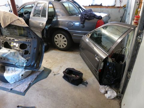 1991 Ford LTD Crown Victoria - Photograph of cars and detached doors in a garage, not a document.