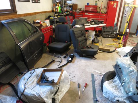 1991 Ford LTD Crown Victoria - Photograph of a garage full of removed car parts and seats, not a document.